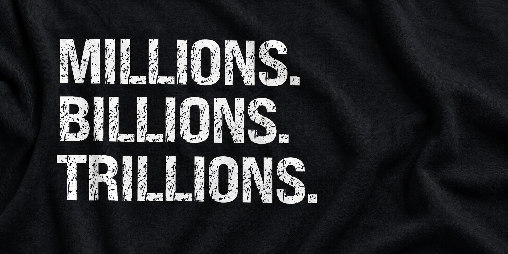 White distressed Millions. Billions. Trillions. lettering on black cotton in a wide editorial close-up